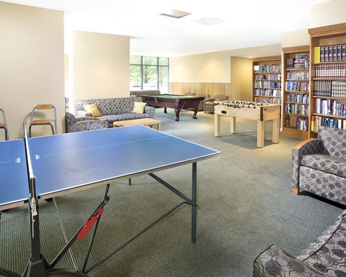 A recreational room with pool tables ping pong and foosball table.