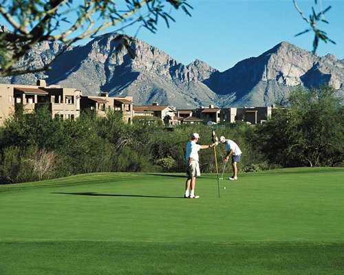 Golfers playing golf at the golf course alongside the mountains.