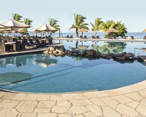 An outdoor swimming pool with chaise lounge chairs and patio furniture.