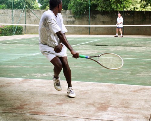 People playing tennis at outdoor tennis court.
