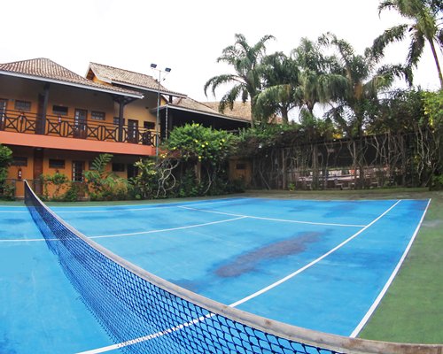 An outdoor tennis court with trees alongside resort units.