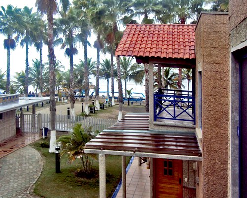 A unit with balcony and palm trees alongside the sea.
