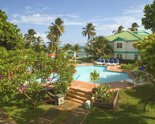 An outdoor swimming pool with chaise lounge chairs and landscaping alongside resort units.