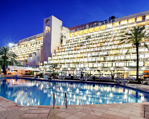 Night view of an outdoor swimming pool alongside the multi story Club Hotel Tiberias.