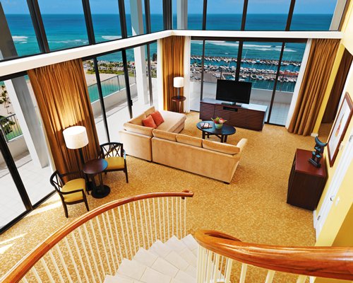 A well furnished living room with a staircase television and an outside view.