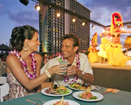 A couple at an outdoor dining and entertainment show having food and beverages.