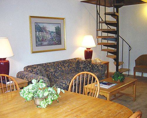 A well furnished living room with dining area and spiral stairway.