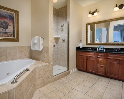 A bathroom with bathtub stand up shower and double sink vanity.