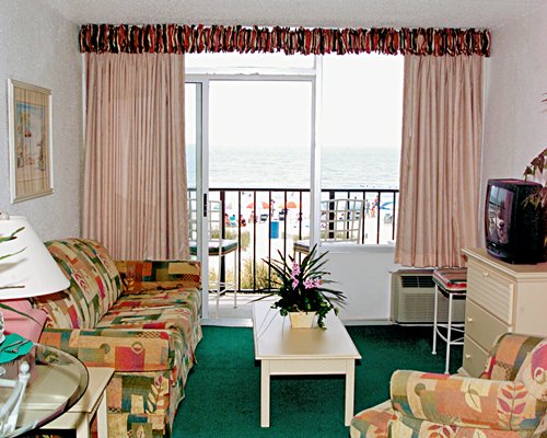 A well furnished living room with a television alongside the ocean.