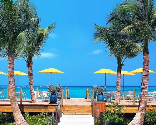 A pathway leading to the beach alongside the patio furniture with sunshades.