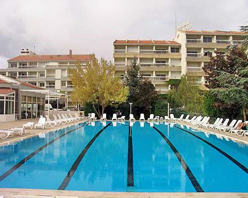 An outdoor swimming pool with chaise lounge chairs alongside the multi story resort units.