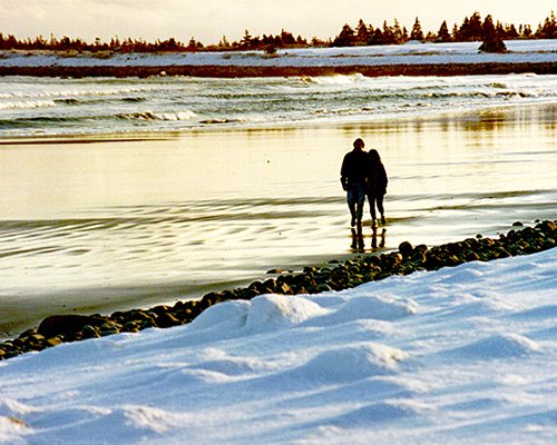Couple walking on the beach during winter.