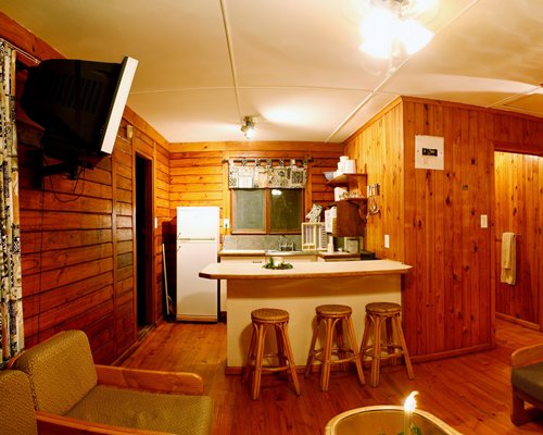 A well furnished living room with a television alongside the kitchen with a breakfast bar.