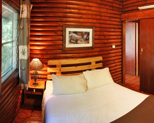 A wooden themed bedroom with a double bed and an outside view.