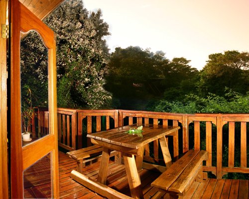 Balcony with picnic table surrounded by wooded area.
