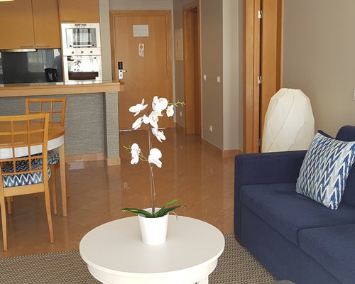 A well furnished living and dining area with a television alongside the kitchen.