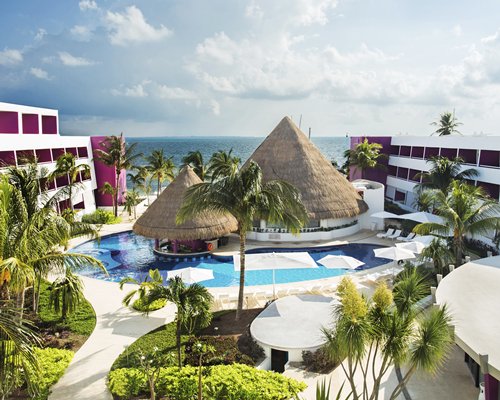 An outdoor swimming pool with swim up bar and chaise lounge chairs alongside the resort units.