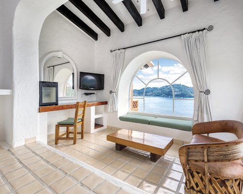 A furnished living room with a television alongside the beach.