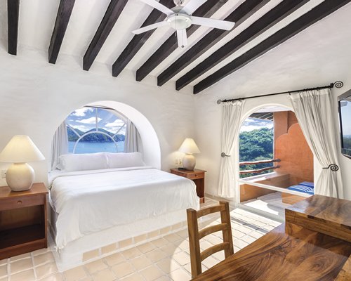 A well furnished bedroom with a king bed and outside view.
