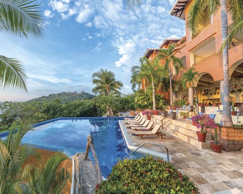 Outdoor swimming pool with chaise lounge chairs alongside multiple balconies.