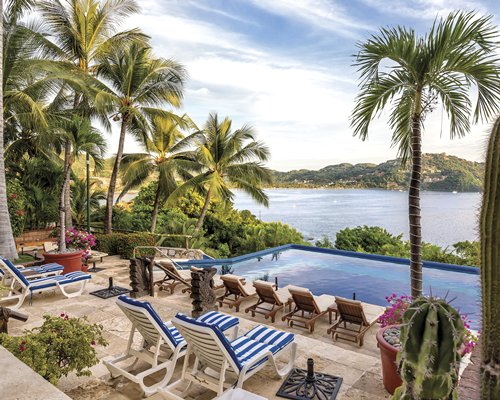 An outdoor swimming pool with chaise lounge chairs alongside the waterfront.