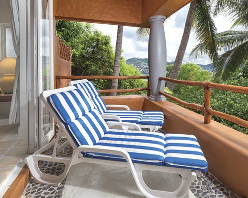 View of chaise lounge chairs in a balcony and an outside view.