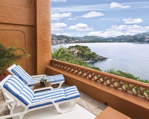 Balcony with chaise lounge chairs and view of the ocean.
