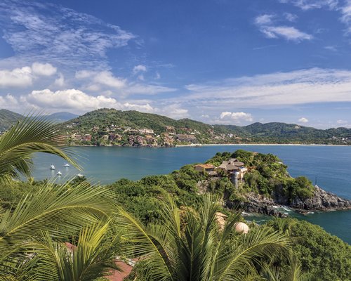 View of the resort properties alongside the ocean surrounded by wooded area.
