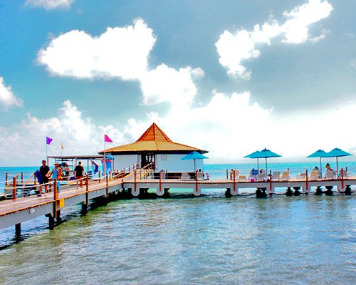 A pier with chaise lounge chairs and sunshades.
