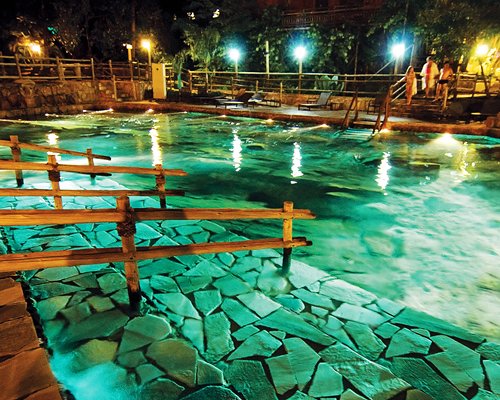 An outdoor swimming pool with chaise lounge chairs at night.