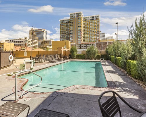 An outdoor swimming pool with chaise lounge chairs alongside resort condos.