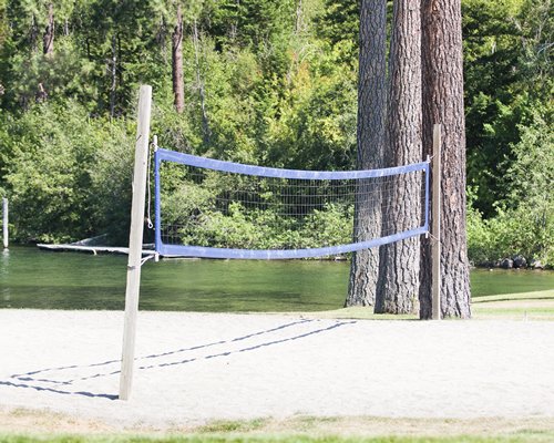 A volleyball court alongside a waterfront and a wooded area.