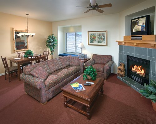 An open plan living dining area with television and fire at the fireplace.