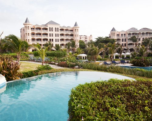 A scenic outdoor swimming pool with chaise lounge chairs alongside multi story condos.