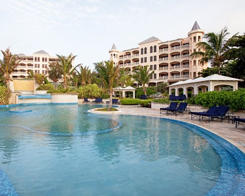 An outdoor swimming pool with chaise lounge chairs alongside resort condos.