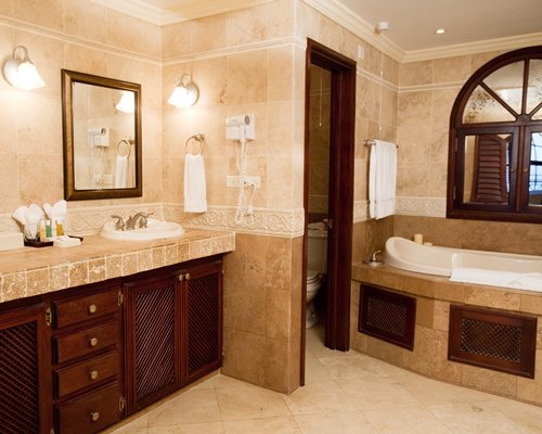 A bathroom with open sink vanity toilet and shower & bathtub.