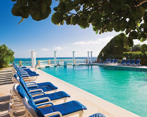 An outdoor swimming pool with chaise lounge chairs.