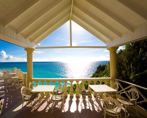A view of an outdoor dining with patio furniture alongside an ocean view.