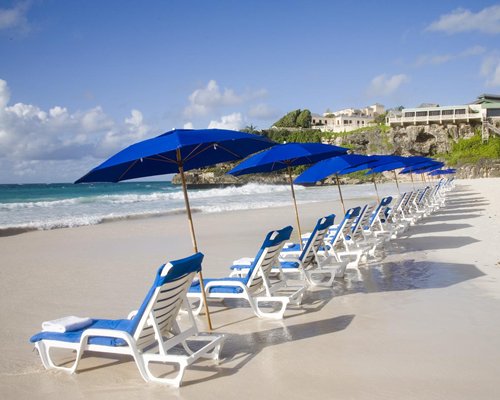 Chaise lounge chairs and sunshades facing the beach.