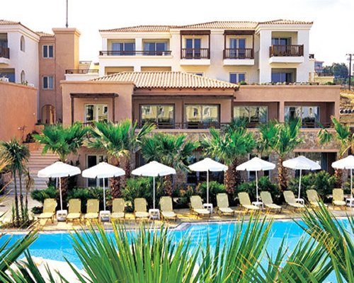 An outdoor swimming pool with chaise lounge chairs alongside resort condo.