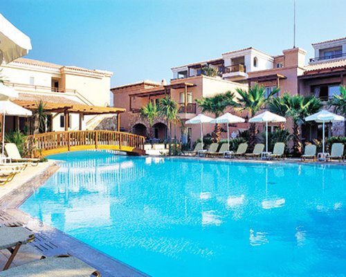 An outdoor swimming pool with chaise lounge chairs alongside resort condo.