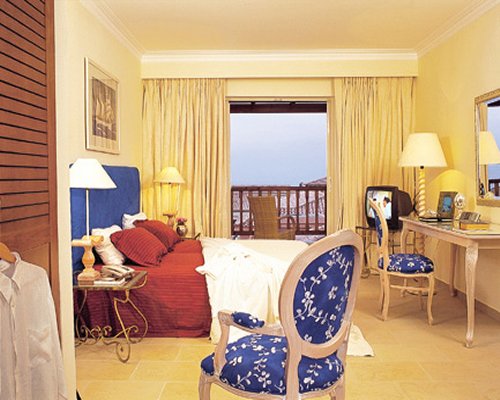 A well furnished bedroom with a bed television vanity and patio.