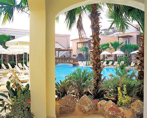Scenic an outdoor swimming pool with chaise lounge chairs surrounded by palm trees alongside resort.