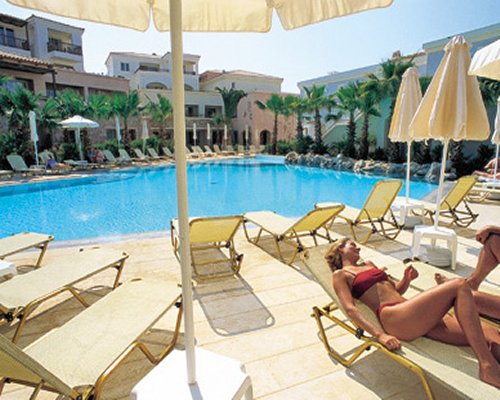 An outdoor swimming pool with chaise lounge chairs alongside multi story condos.