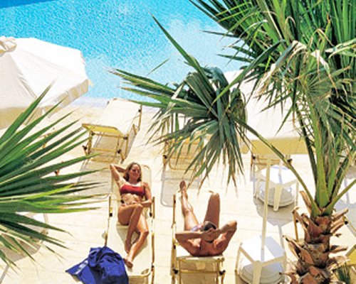 A couple in chaise lounge chairs alongside the pool.