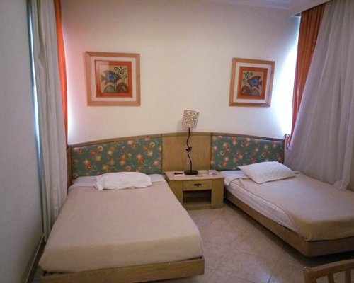 A well furnished bedroom with two twin beds television and balcony.