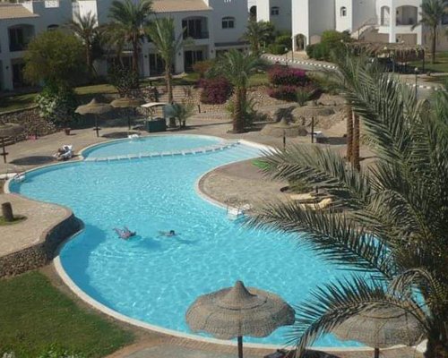 An outdoor swimming pool with chaise lounge chairs alongside the multiple story condo.
