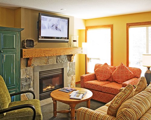 A well furnished living room with queen pull out sofa television and fire in the fireplace.