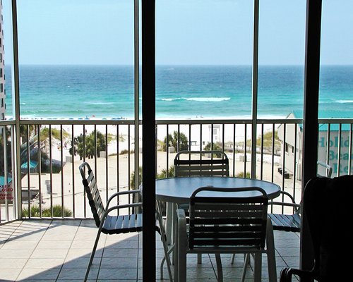 A balcony with patio furniture facing the beach.