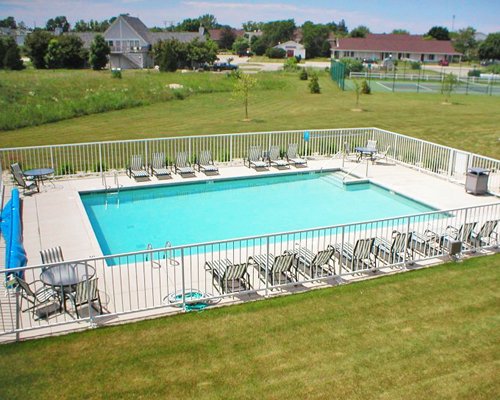 An outdoor swimming pool with patio and chaise lounge chairs.